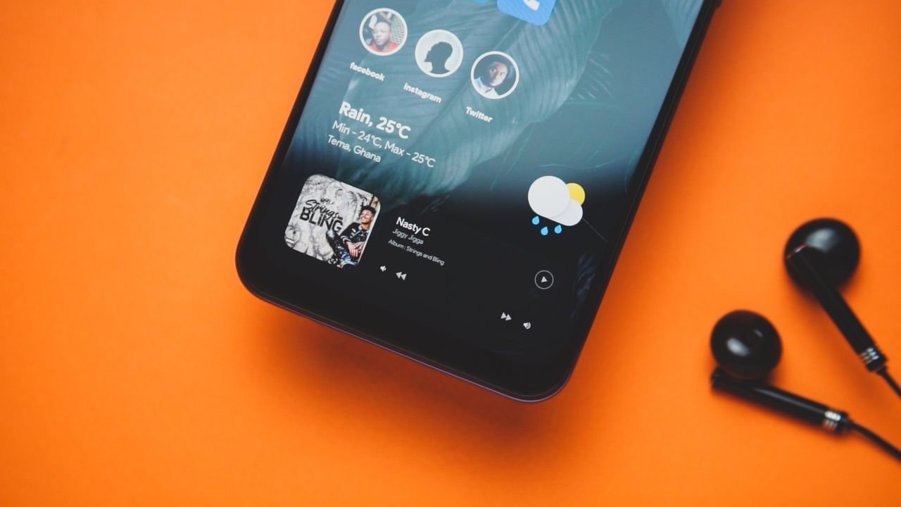 Services Close-up of a smartphone with earphones on an orange background showing a music playlist and weather update.