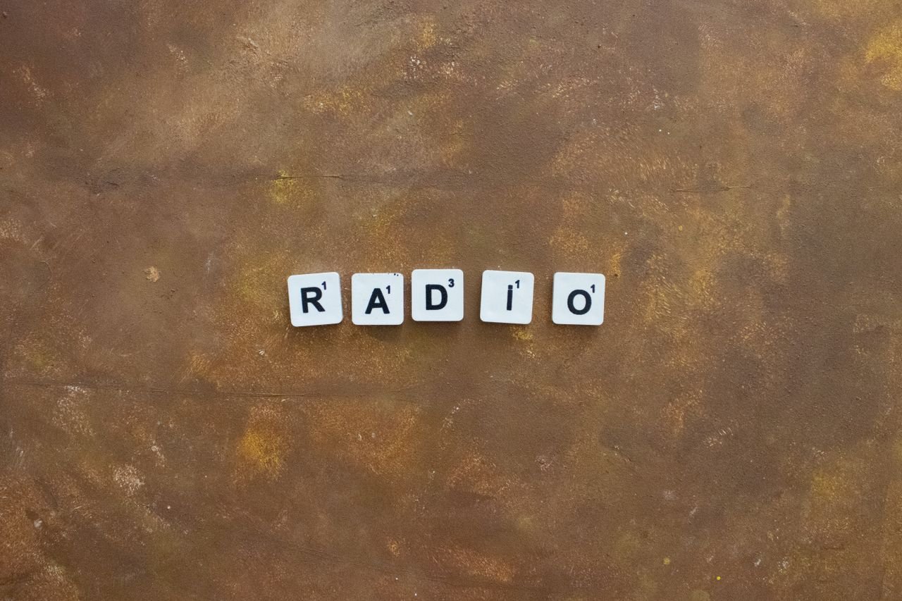 Services Close-up of Scrabble tiles spelling 'Radio' on a rustic brown background.
