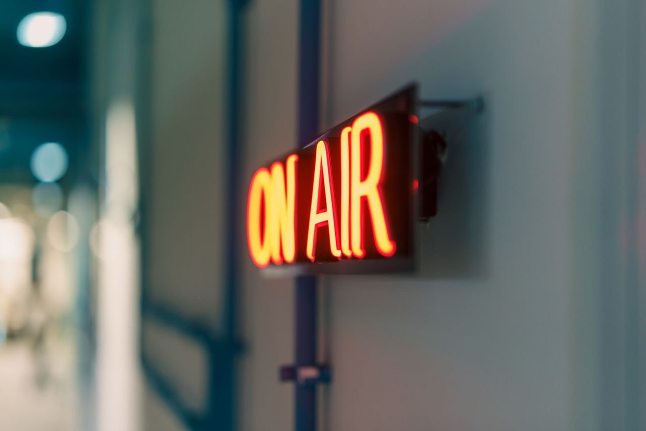 Home Bright red 'On Air' neon sign captured indoors, ideal for media content.