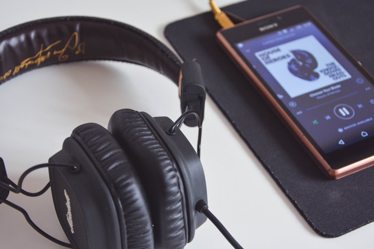 Services A close-up of headphones and a smartphone playing music on a desk.